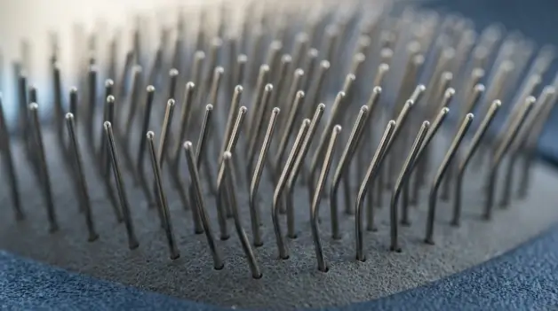 Macro view of polished stainless steel pins on an ergonomic slicker brush for dogs